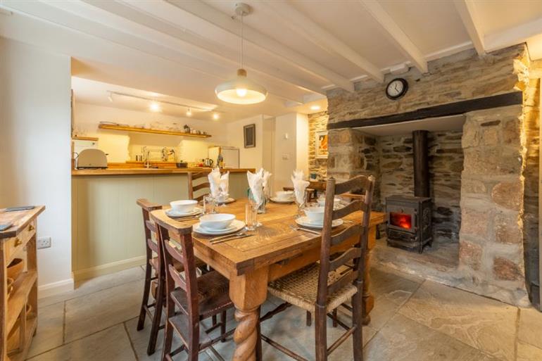 Dining area with table and a inglenook fireplace with wood burning stove at Rose in Vale Cottage,